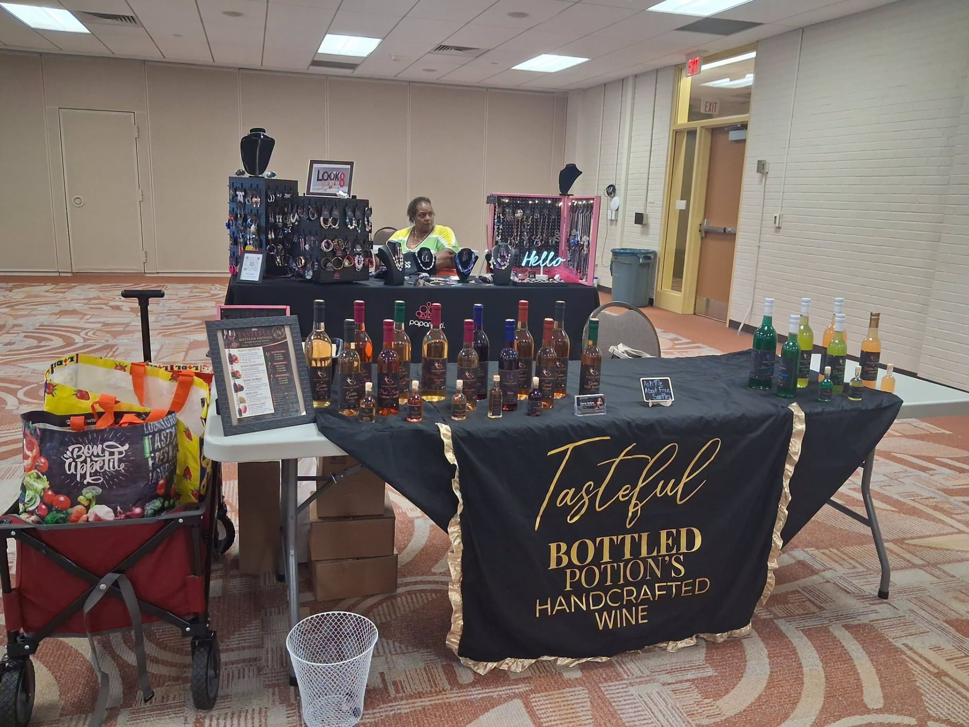 A vendor table of handcrafted bottled wines and jewelry at the event.