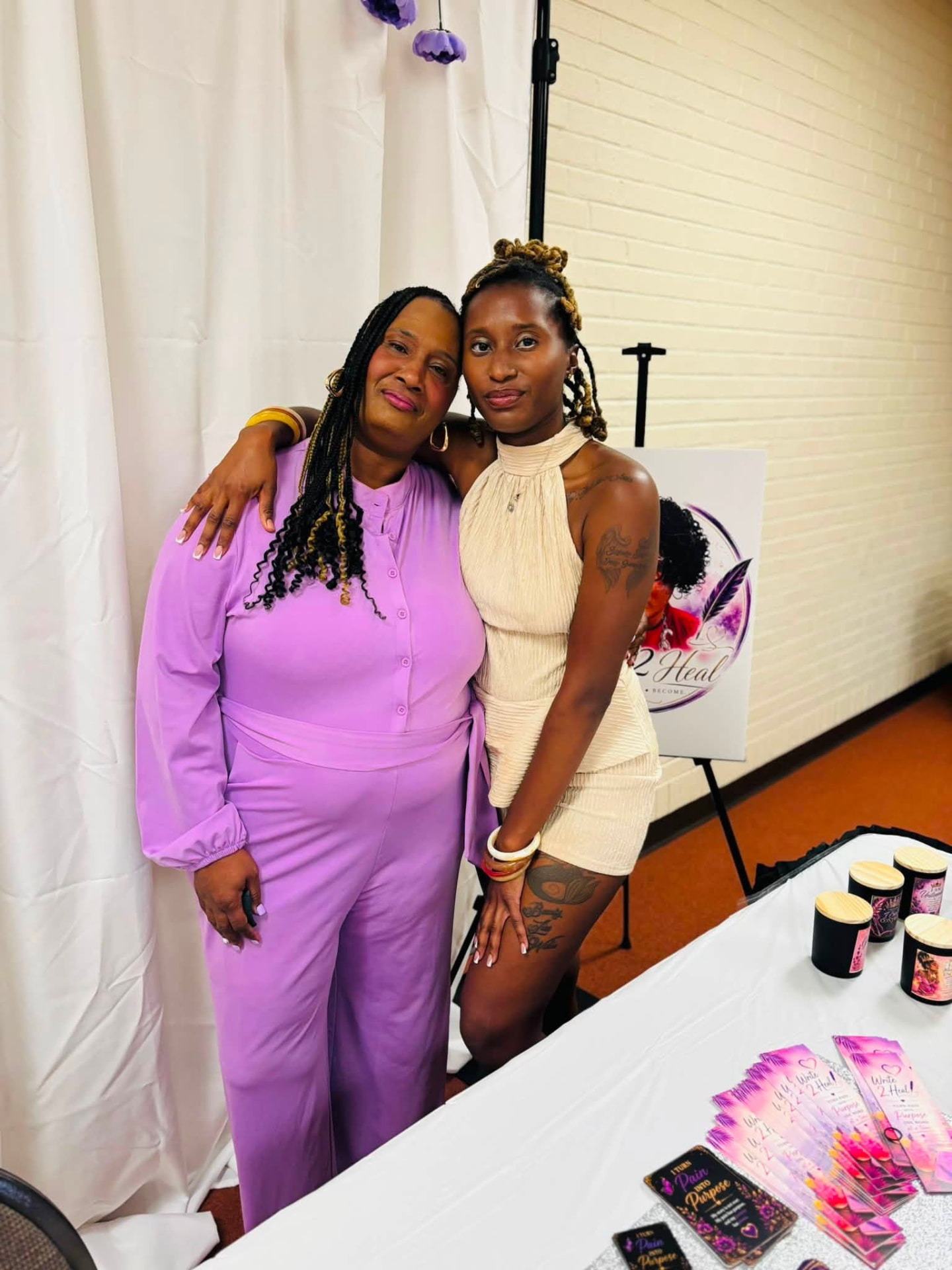 Roslyn Thompson embracing a guest in front of the Write 2 Heal display.