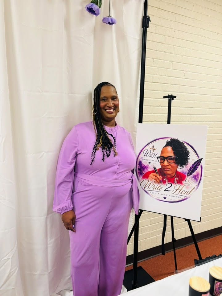 Roslyn Thompson standing beside the Write 2 Heal logo display at Summer Wine Down: Sip & Sign.