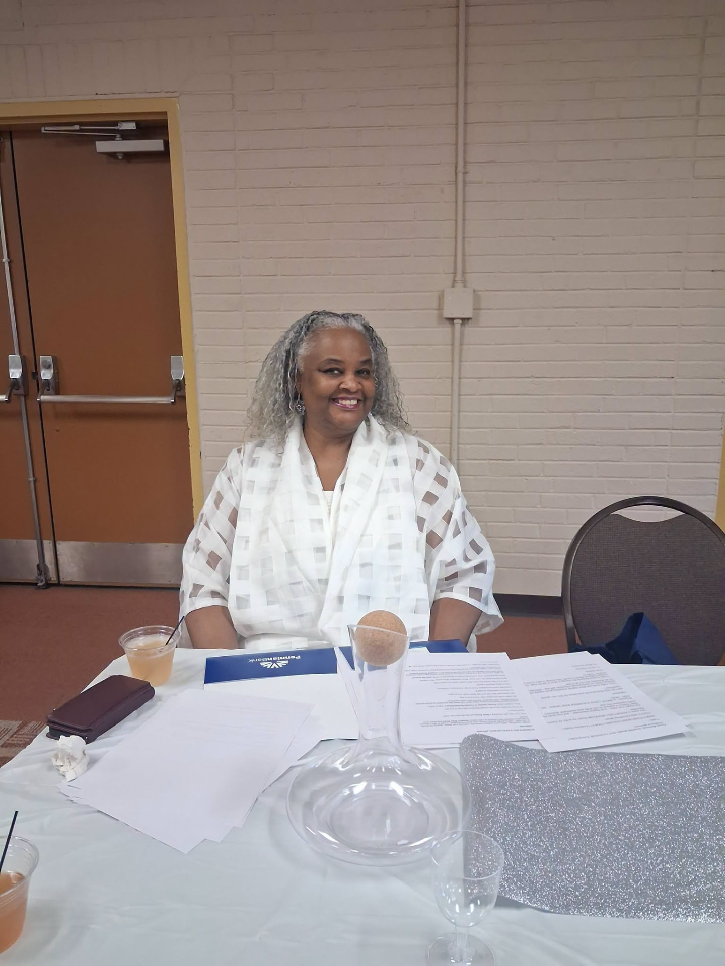 A guest seated at a table with event programs and wine glasses.